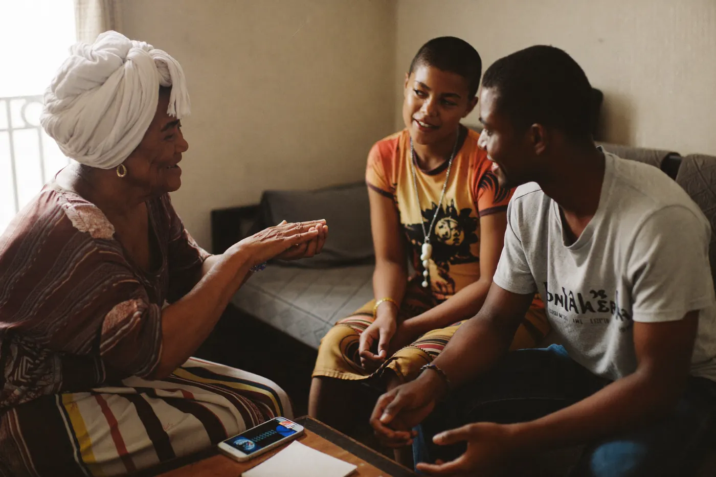 Trois générations d'une famille discutent autour d'une table basse.